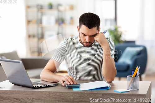 Image of man with files and calculator works at home office