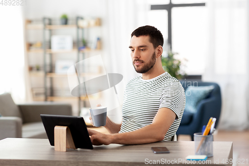 Image of man with tablet pc drinking coffee at home office