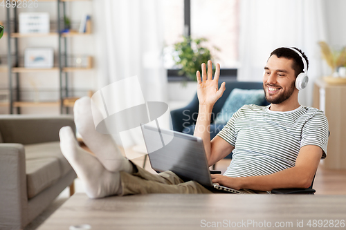 Image of man with laptop and headphones having video call