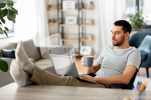 Image of man with laptop drinking coffee at home
