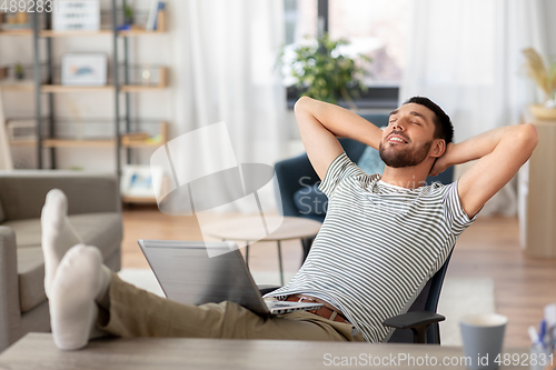 Image of happy man with laptop resting at home office