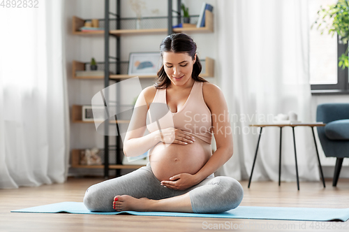 Image of happy pregnant woman doing yoga at home