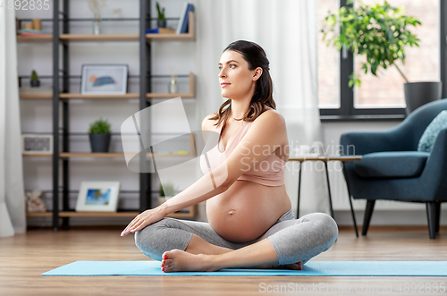 Image of happy pregnant woman doing yoga at home