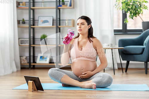 Image of pregnant woman drinking water after yoga at home