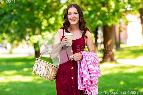 Image of happy woman with picnic basket and coffee at park