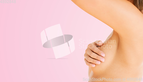 Image of young woman checking breast for signs of cancer