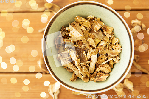 Image of dried mushrooms in bowl on wooden background