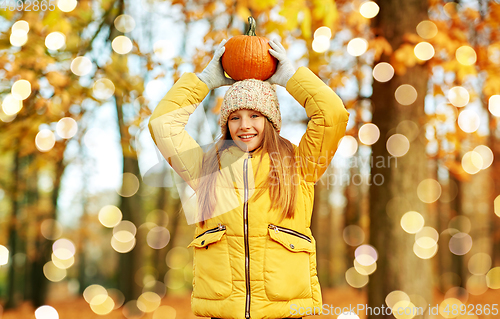 Image of happy girl with pumpkin at autumn park