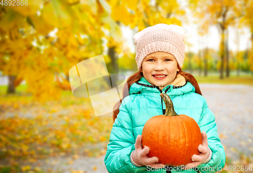 Image of happy redhead girl with pumpkin at autumn park