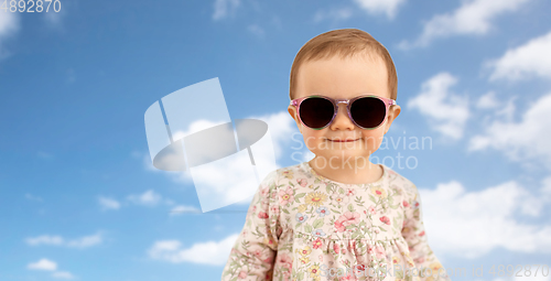 Image of happy little baby girl in sunglasses over blue sky