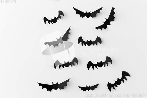 Image of flock of black paper bats over white background