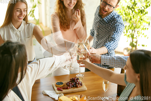 Image of People clinking glasses with wine or champagne. Happy cheerful friends celebrate holidays, meeting. Close up shot of smiling friends, lifestyle