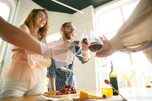 Image of People clinking glasses with wine or champagne. Happy cheerful friends celebrate holidays, meeting. Close up shot of smiling friends, lifestyle