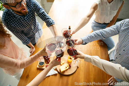 Image of People clinking glasses with wine or champagne. Happy cheerful friends celebrate holidays, meeting. Close up shot of smiling friends, lifestyle