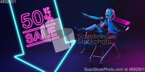 Image of Portrait of young woman in neon light on dark backgound. The human emotions, black friday, cyber monday, purchases, sales, finance concept. Neoned lettering.