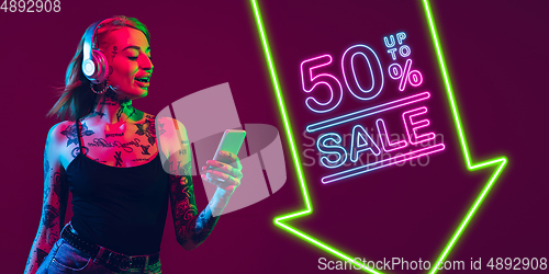 Image of Portrait of young woman in neon light on dark backgound. The human emotions, black friday, cyber monday, purchases, sales, finance concept. Neoned lettering.