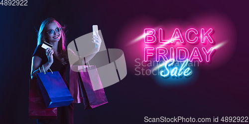 Image of Portrait of young woman in neon light on dark backgound. The human emotions, black friday, cyber monday, purchases, sales, finance concept. Neoned lettering.