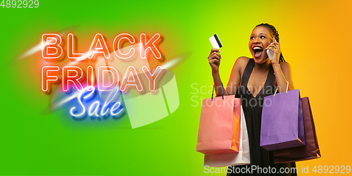 Image of Portrait of young woman in neon light on gradient backgound. The human emotions, black friday, cyber monday, purchases, sales, finance concept. Neoned lettering.