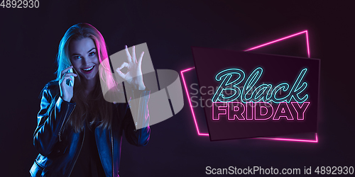 Image of Portrait of young woman in neon light on dark backgound. The human emotions, black friday, cyber monday, purchases, sales, finance concept. Neoned lettering.