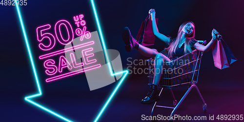 Image of Portrait of young woman in neon light on dark backgound. The human emotions, black friday, cyber monday, purchases, sales, finance concept. Neoned lettering.