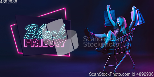 Image of Portrait of young woman in neon light on dark backgound. The human emotions, black friday, cyber monday, purchases, sales, finance concept. Neoned lettering.