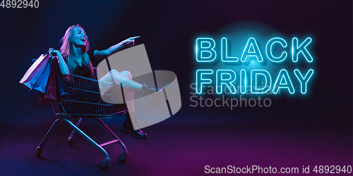 Image of Portrait of young woman in neon light on dark backgound. The human emotions, black friday, cyber monday, purchases, sales, finance concept. Neoned lettering.