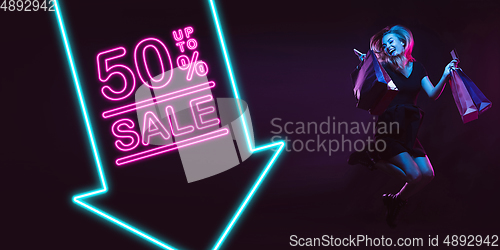 Image of Portrait of young woman in neon light on dark backgound. The human emotions, black friday, cyber monday, purchases, sales, finance concept. Neoned lettering.