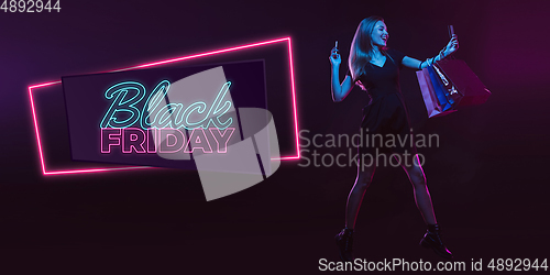 Image of Portrait of young woman in neon light on dark backgound. The human emotions, black friday, cyber monday, purchases, sales, finance concept. Neoned lettering.