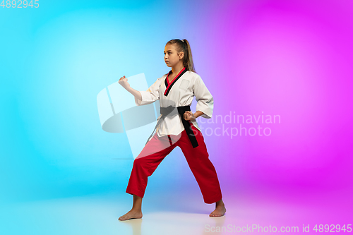 Image of Karate, taekwondo girl with black belt isolated on gradient background in neon light