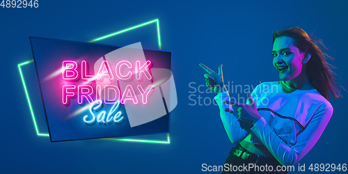 Image of Portrait of young woman in neon light on blue backgound. The human emotions, black friday, cyber monday, purchases, sales, finance concept. Neoned lettering.