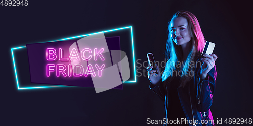 Image of Portrait of young woman in neon light on dark backgound. The human emotions, black friday, cyber monday, purchases, sales, finance concept. Neoned lettering.