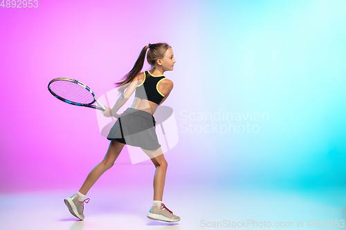 Image of Little tennis girl in black sportwear isolated on gradient background in neon light