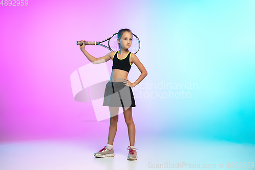 Image of Little tennis girl in black sportwear isolated on gradient background in neon light