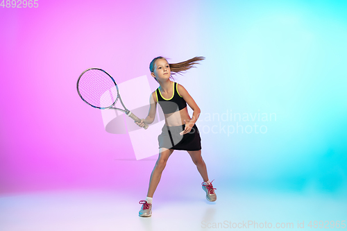 Image of Little tennis girl in black sportwear isolated on gradient background in neon light