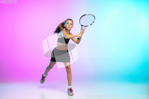 Image of Little tennis girl in black sportwear isolated on gradient background in neon light