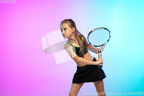 Image of Little tennis girl in black sportwear isolated on gradient background in neon light