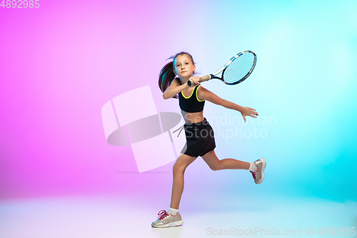 Image of Little tennis girl in black sportwear isolated on gradient background in neon light