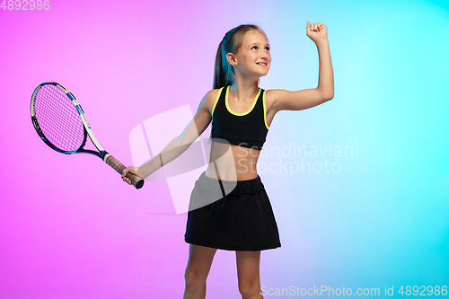 Image of Little tennis girl in black sportwear isolated on gradient background in neon light