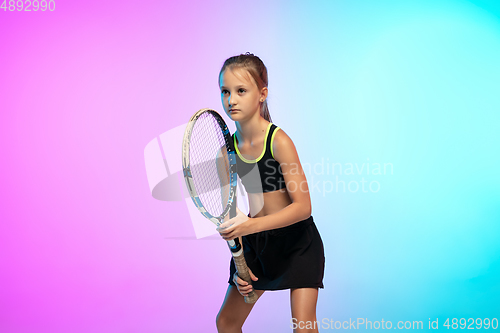 Image of Little tennis girl in black sportwear isolated on gradient background in neon light