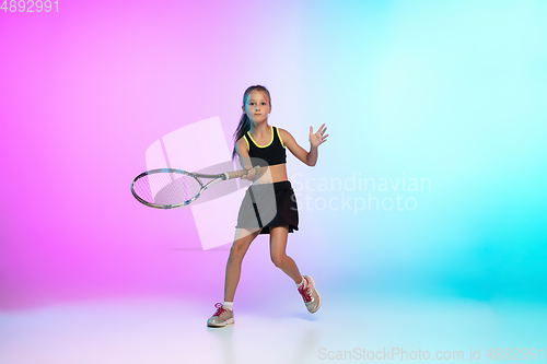 Image of Little tennis girl in black sportwear isolated on gradient background in neon light