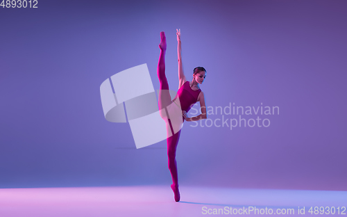 Image of Young and graceful ballet dancer isolated on purple studio background in neon light