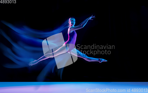 Image of Young and graceful ballet dancer isolated on black studio background in neon mixed light