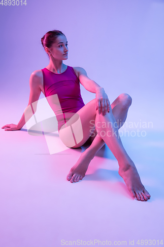 Image of Young and graceful ballet dancer isolated on purple studio background in neon light