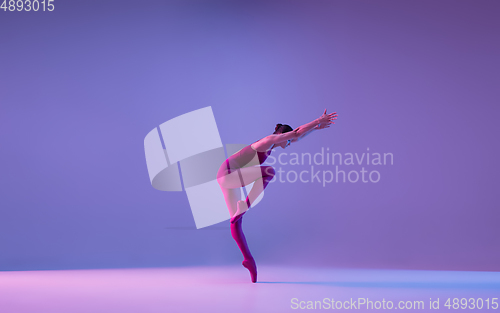 Image of Young and graceful ballet dancer isolated on purple studio background in neon light