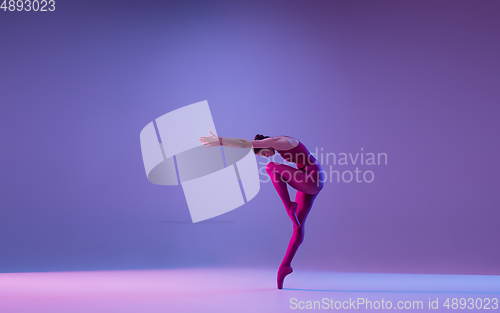 Image of Young and graceful ballet dancer isolated on purple studio background in neon light