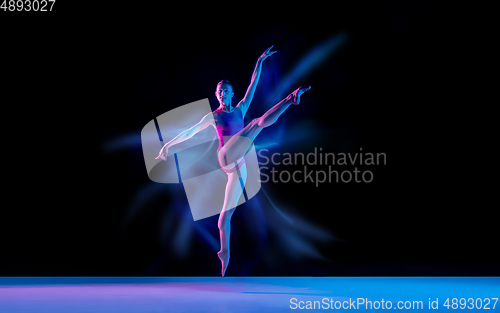 Image of Young and graceful ballet dancer isolated on black studio background in neon mixed light