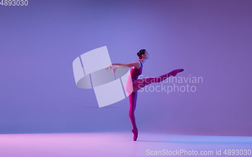Image of Young and graceful ballet dancer isolated on purple studio background in neon light