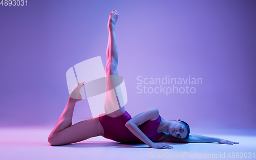 Image of Young and graceful ballet dancer isolated on purple studio background in neon light