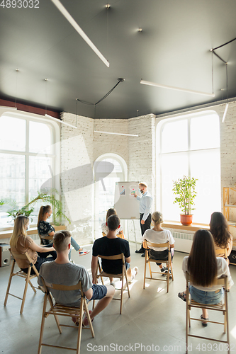 Image of Male speaker giving presentation in hall at university workshop. Audience or conference hall