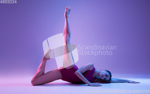 Image of Young and graceful ballet dancer isolated on purple studio background in neon light